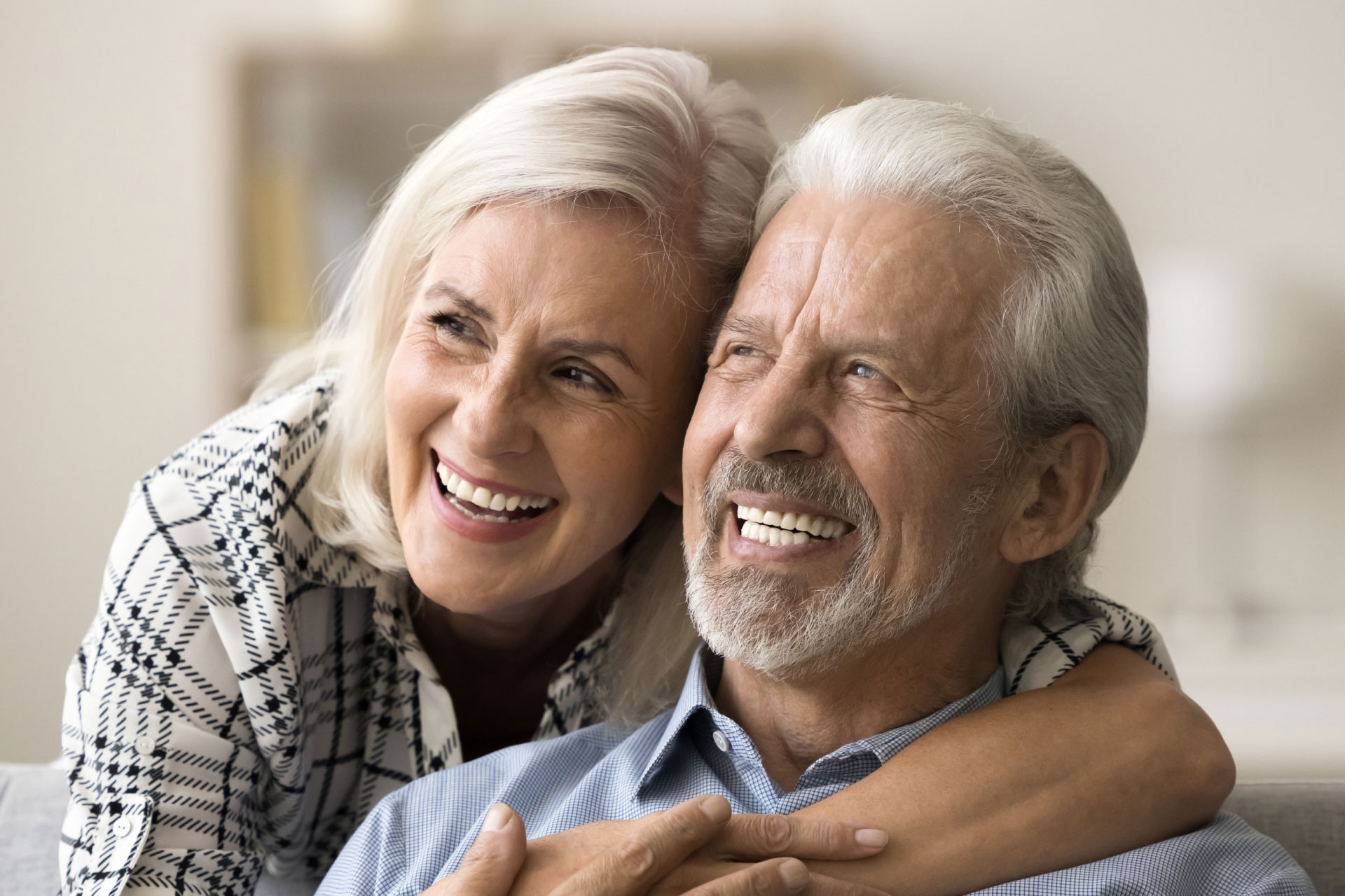 mature couple hugging, looking to the left and smiling